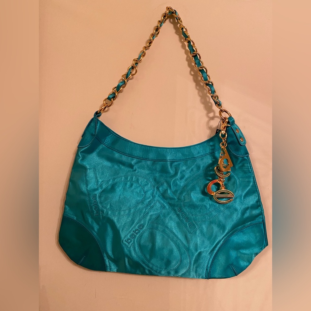 Bebe neon blue aquamarine color nylon bag with with gold tone accent charms.